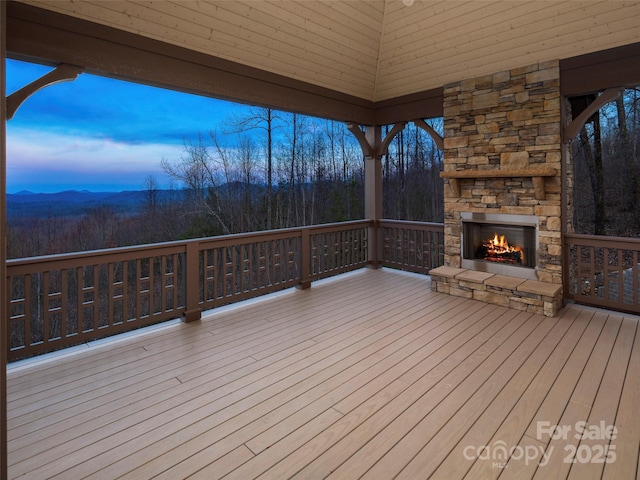 wooden deck with an outdoor stone fireplace