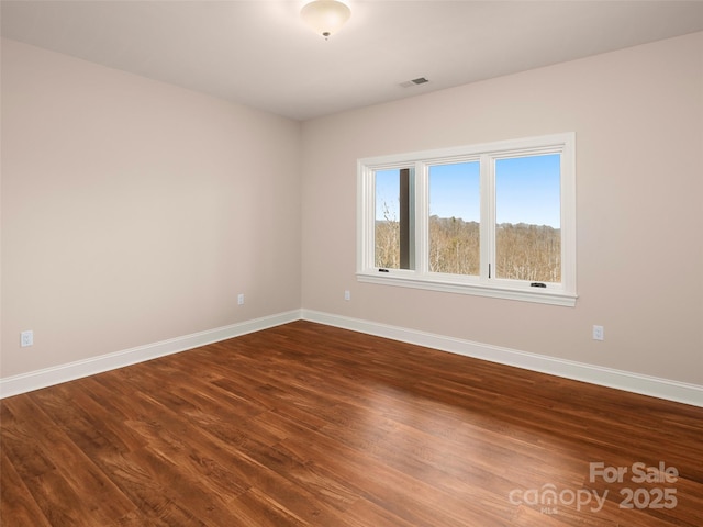 unfurnished room with visible vents, baseboards, and wood finished floors