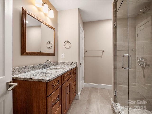 bathroom featuring vanity, a shower stall, and baseboards