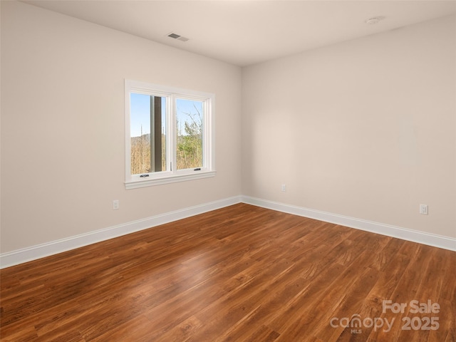 spare room featuring visible vents, baseboards, and wood finished floors