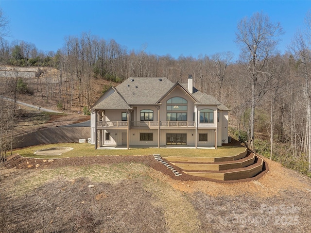 back of property with a patio area, a chimney, a yard, and roof with shingles