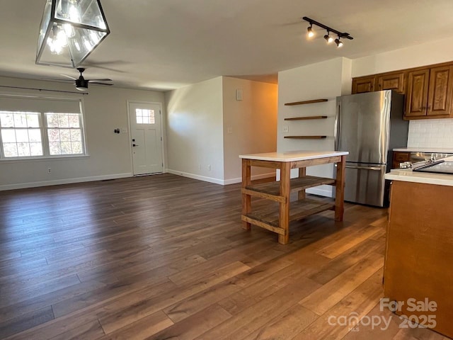 kitchen with dark wood-type flooring, open shelves, tasteful backsplash, freestanding refrigerator, and light countertops