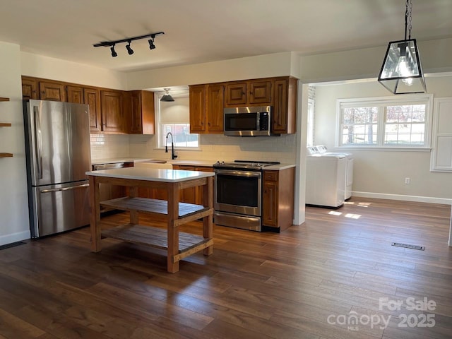 kitchen with stainless steel appliances, independent washer and dryer, dark wood-style floors, and light countertops