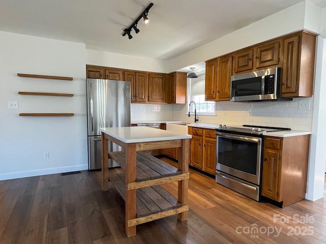 kitchen with dark wood-type flooring, light countertops, backsplash, and stainless steel appliances