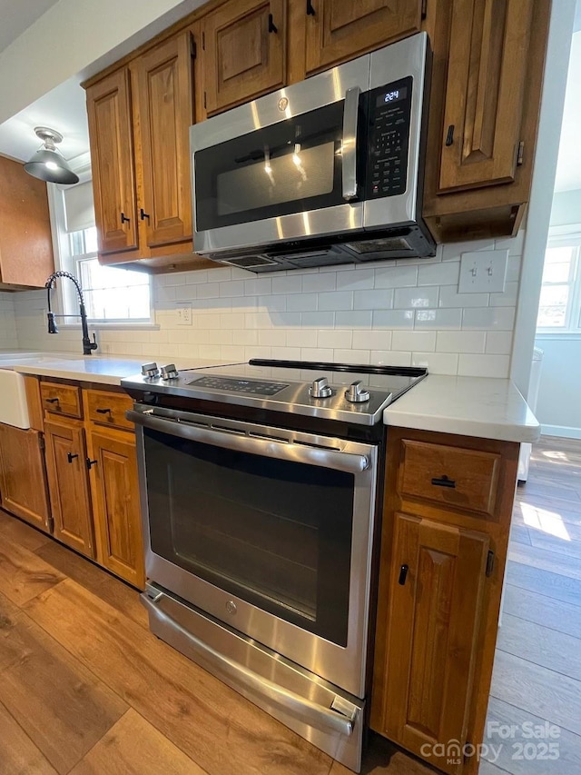 kitchen featuring light wood-style floors, tasteful backsplash, and appliances with stainless steel finishes