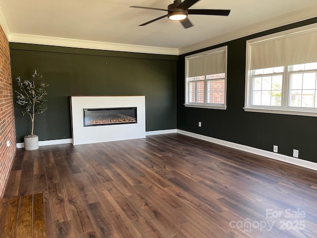 unfurnished living room featuring a glass covered fireplace, crown molding, and wood finished floors