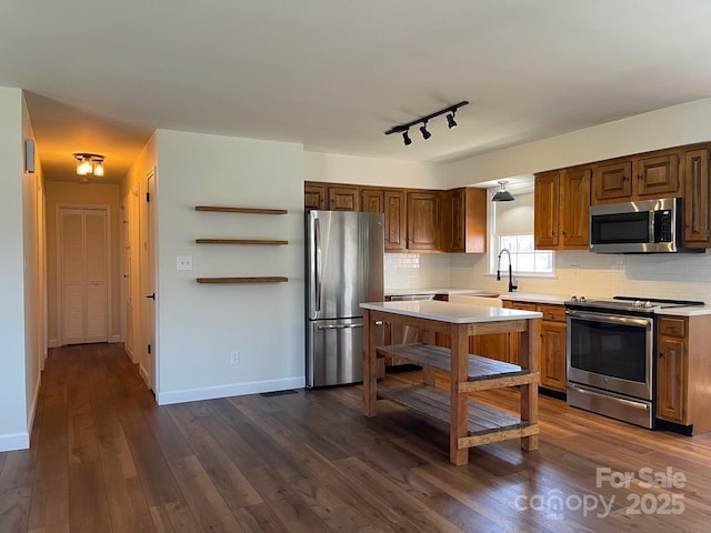 kitchen with appliances with stainless steel finishes, light countertops, and dark wood-style flooring