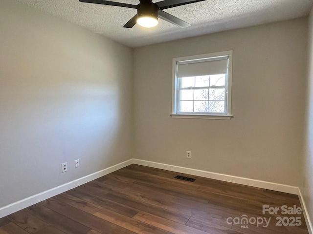 spare room featuring dark wood-style floors, visible vents, a textured ceiling, and baseboards