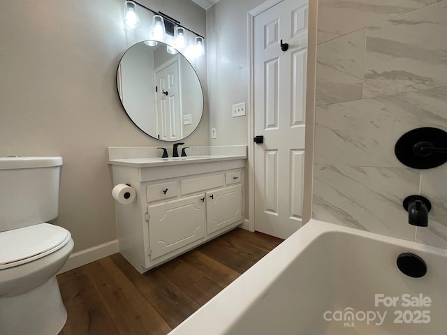 full bath featuring toilet, wood finished floors, vanity, baseboards, and shower / bathtub combination