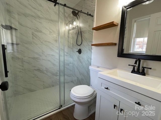 full bath featuring a marble finish shower, toilet, and vanity