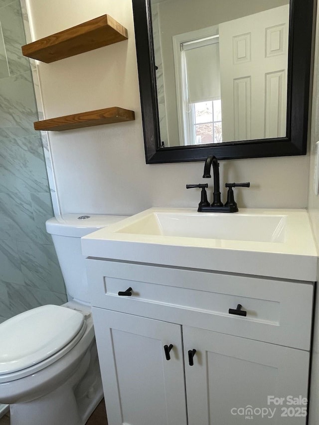 bathroom with vanity, tile walls, and toilet