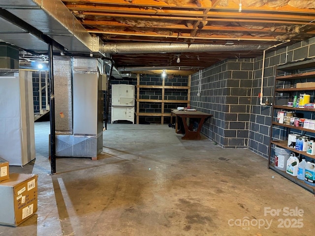 unfinished basement featuring concrete block wall