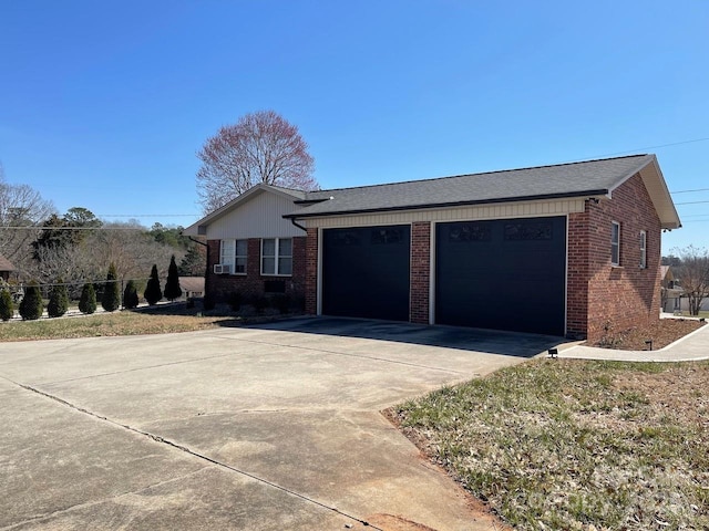 view of home's exterior with brick siding, an attached garage, and concrete driveway