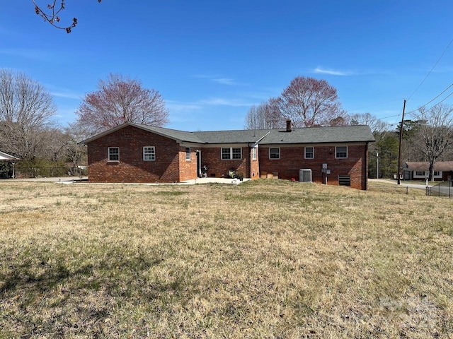 back of property featuring a lawn, brick siding, and central AC