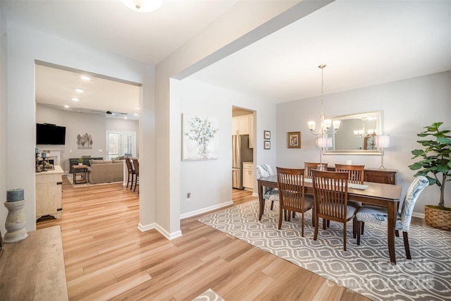 dining space with a notable chandelier, baseboards, and light wood finished floors