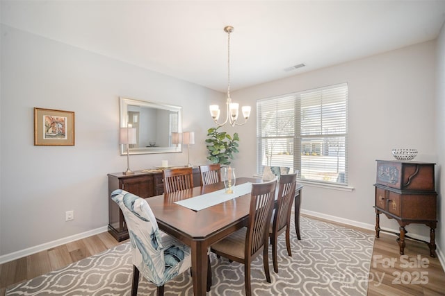 dining room with visible vents, light wood-style flooring, baseboards, and an inviting chandelier