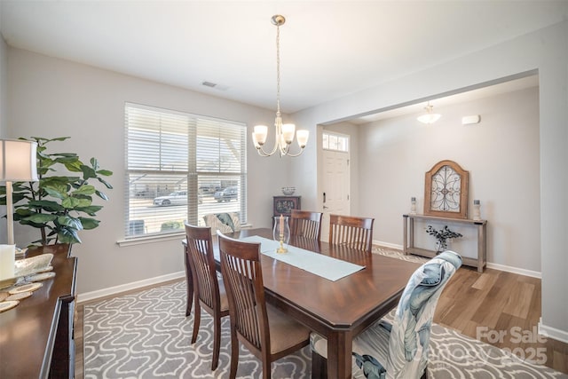 dining room featuring light wood-type flooring, visible vents, baseboards, and an inviting chandelier