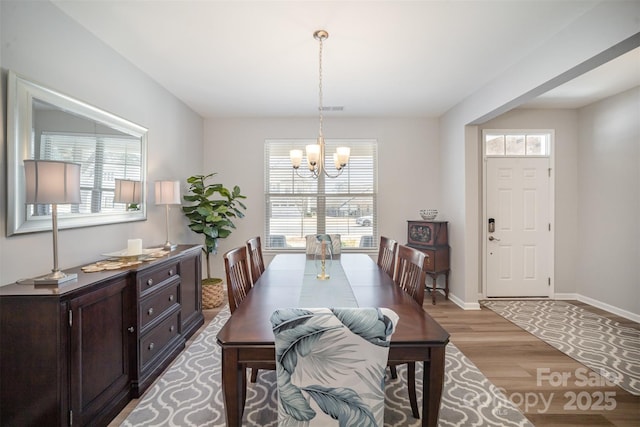 dining room with visible vents, baseboards, a chandelier, and light wood finished floors