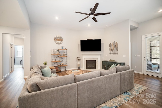 living room featuring baseboards, a fireplace with flush hearth, recessed lighting, wood finished floors, and a ceiling fan