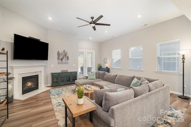 living room featuring a fireplace, recessed lighting, light wood-style floors, and baseboards