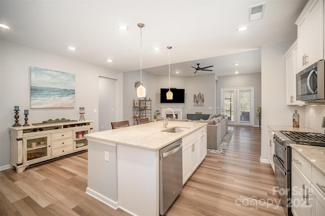 kitchen with a center island with sink, visible vents, a sink, appliances with stainless steel finishes, and open floor plan