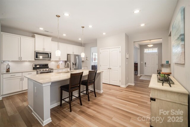 kitchen with visible vents, a sink, appliances with stainless steel finishes, tasteful backsplash, and light wood-type flooring