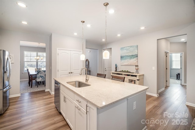 kitchen featuring a center island with sink, recessed lighting, light wood-style flooring, appliances with stainless steel finishes, and a sink