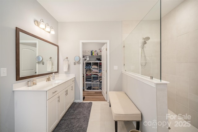 bathroom featuring a spacious closet, tile patterned floors, a walk in shower, and vanity