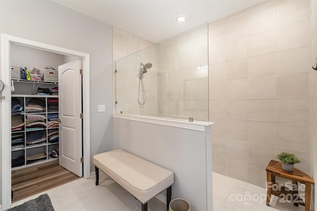 bathroom with a spacious closet, recessed lighting, and a walk in shower