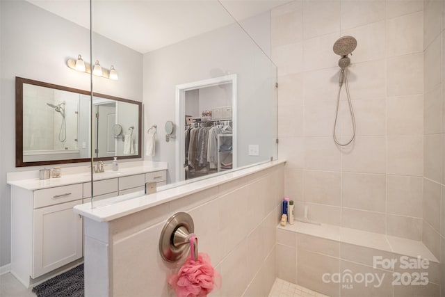 full bath featuring vanity, a spacious closet, and a walk in shower