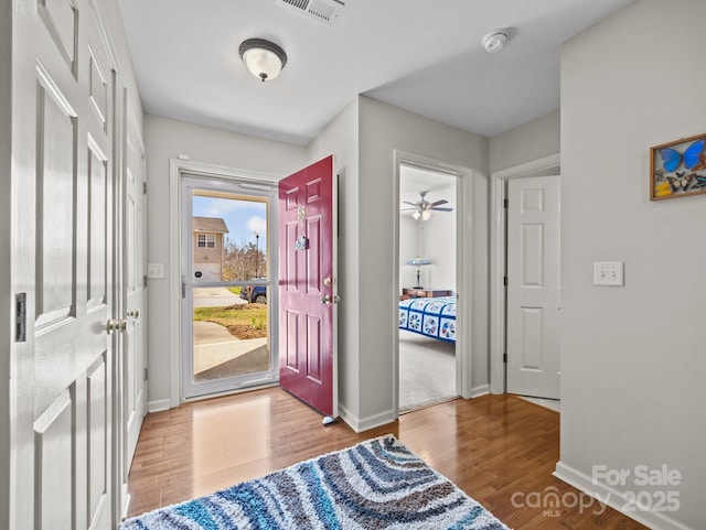 foyer entrance featuring visible vents, ceiling fan, baseboards, and wood finished floors