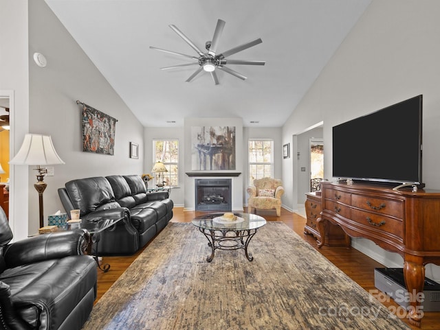 living area with high vaulted ceiling, a ceiling fan, wood finished floors, a fireplace, and baseboards