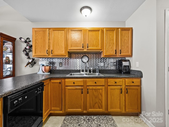 kitchen with dark countertops, black dishwasher, backsplash, and a sink