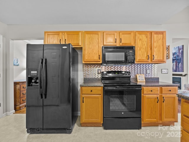 kitchen featuring dark countertops, backsplash, and black appliances