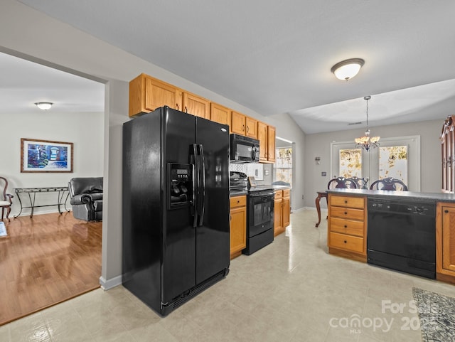 kitchen with pendant lighting, black appliances, an inviting chandelier, baseboards, and vaulted ceiling