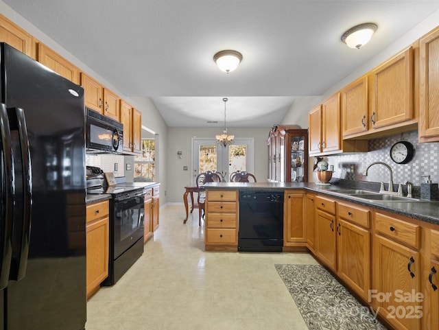 kitchen with a peninsula, a sink, black appliances, dark countertops, and tasteful backsplash