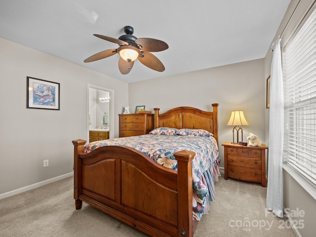 bedroom with a ceiling fan, light colored carpet, baseboards, and connected bathroom