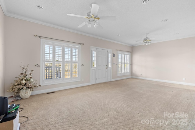 carpeted foyer featuring visible vents, crown molding, baseboards, and ceiling fan