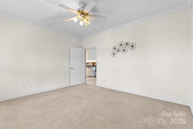 empty room featuring light colored carpet, crown molding, baseboards, and ceiling fan