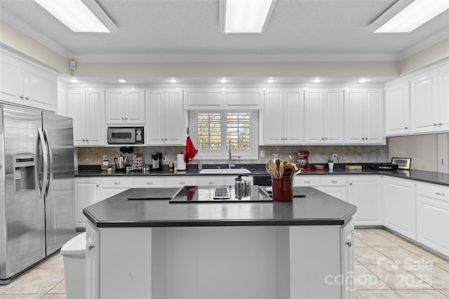 kitchen featuring a sink, white cabinetry, appliances with stainless steel finishes, a center island, and dark countertops