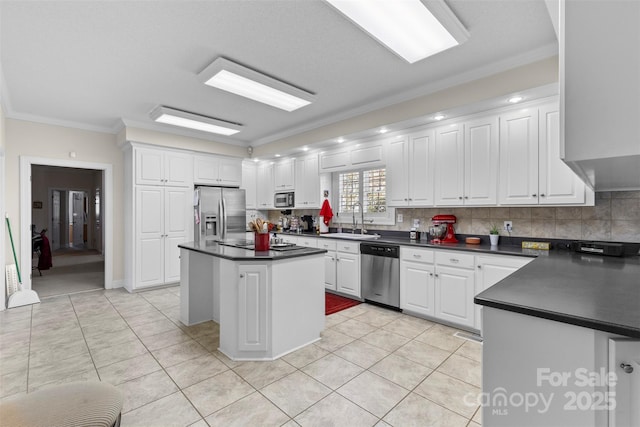 kitchen featuring stainless steel appliances, dark countertops, white cabinetry, and a sink