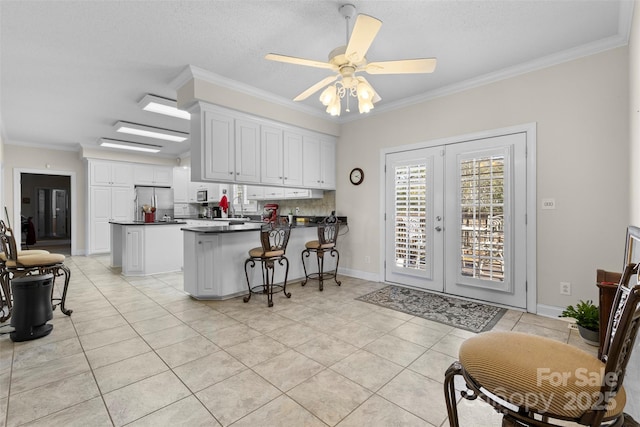 kitchen featuring french doors, dark countertops, ornamental molding, freestanding refrigerator, and a peninsula