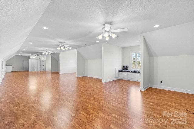 additional living space featuring lofted ceiling, baseboards, a textured ceiling, and light wood finished floors