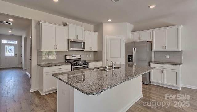 kitchen with stainless steel appliances, white cabinets, visible vents, and a sink