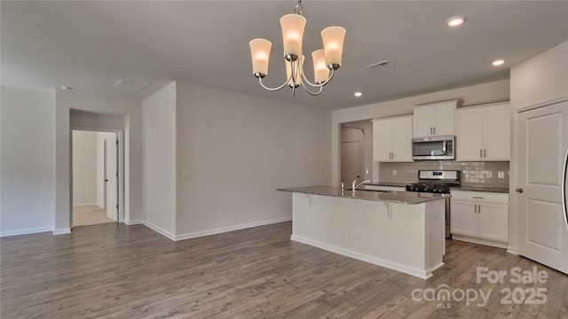 kitchen with visible vents, decorative backsplash, wood finished floors, stainless steel appliances, and a sink