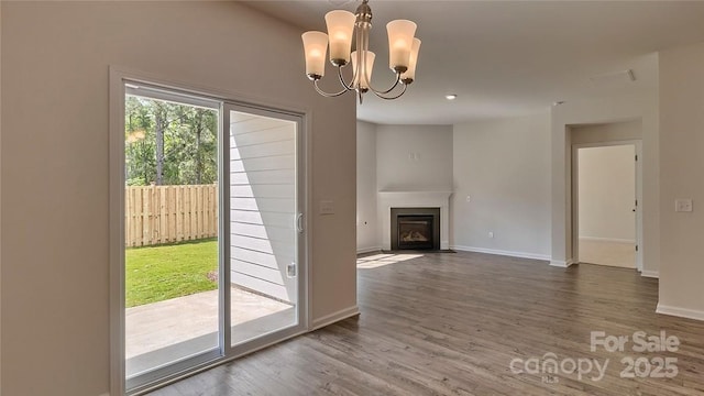 entryway with a fireplace with flush hearth, a chandelier, wood finished floors, and baseboards