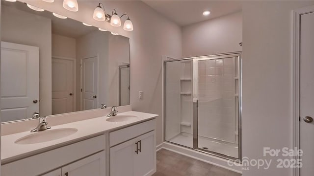 bathroom featuring a stall shower, a sink, and double vanity