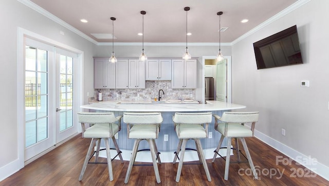 kitchen with tasteful backsplash, light countertops, freestanding refrigerator, a sink, and a kitchen breakfast bar