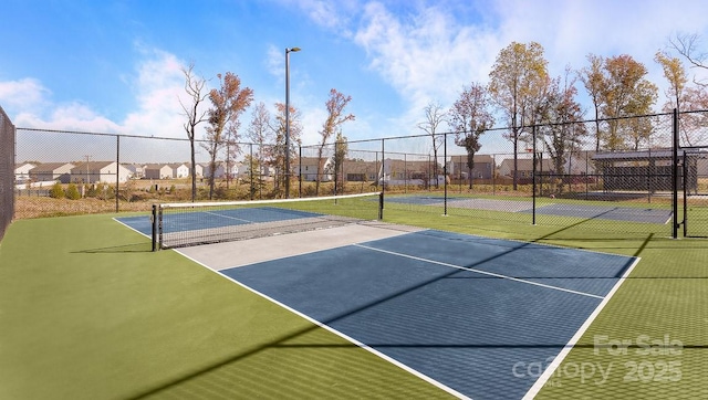 view of tennis court featuring a residential view and fence