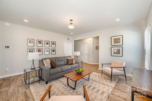 living area with recessed lighting, visible vents, baseboards, and light wood finished floors